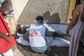 Een medewerker in het Al Hashaba transitie kamp helpt een patiënt.