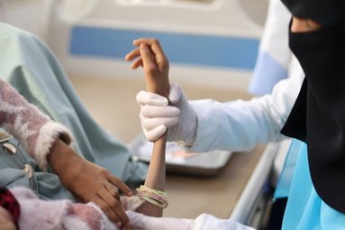 Verpleegkundige helpt een ondervoed kind rechtop zitten
