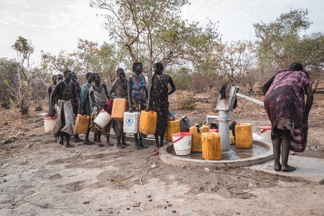 rouwen in het dorp Akelo, Labarab, staan te kletsen, terwijl ze wachten op hun beurt om water uit het boorgat te halen.