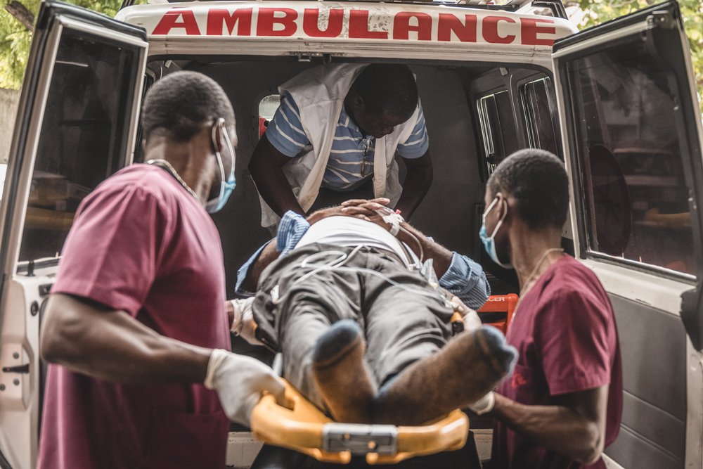 Hulpverleners van Artsen zonder Grenzen tillen een patiënt de ambulance in.