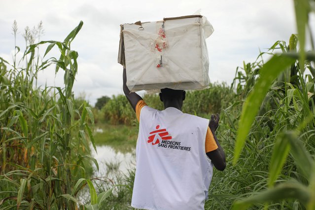 Een hulpverlener draagt een doos met medicijnen door het moeras in Zuid-Soedan