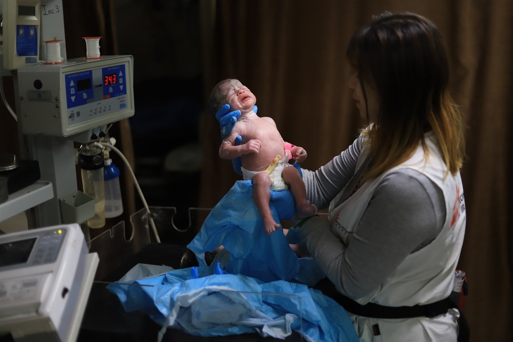 manager verloskunde houdt baby in de lucht in gaza
