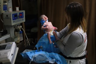 manager verloskunde houdt baby in de lucht in gaza