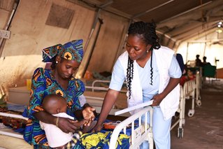 kindje zit op schoot van moeder en krijgt behandeling tegen ondervoeding