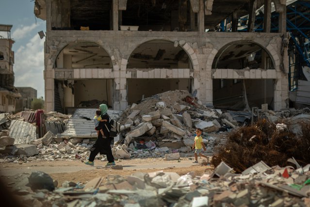Een vrouw draagt haar kind door de Baghdadstraat in de wijk Shujaeyya, Gaza-Stad. © Motassem Abu Aser
