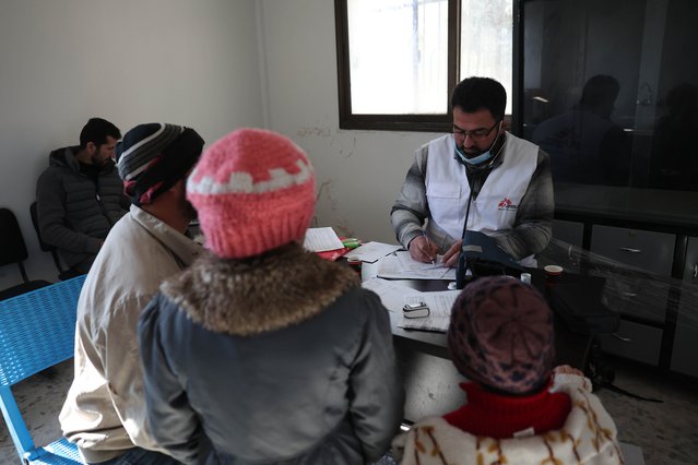 Vanuit een mobiele kliniek schrijft Mohammed Gobasi medicatie voor aan een vader en zijn twee kinderen. © Omar Haj Kadour