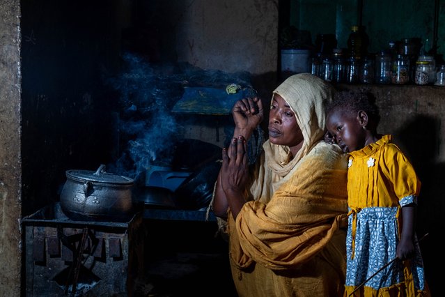 Asia (30) kookt op een vuurtje terwijl haar vijfjarige dochter Masajid toekijkt. Het gezin is gevlucht uit Khartoem. © Moises Saman/Magnum Photos