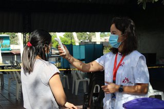 Hulpverlener meet de temperatuur van een inwoner uit Colonia Las Margaritas, El Salvador.