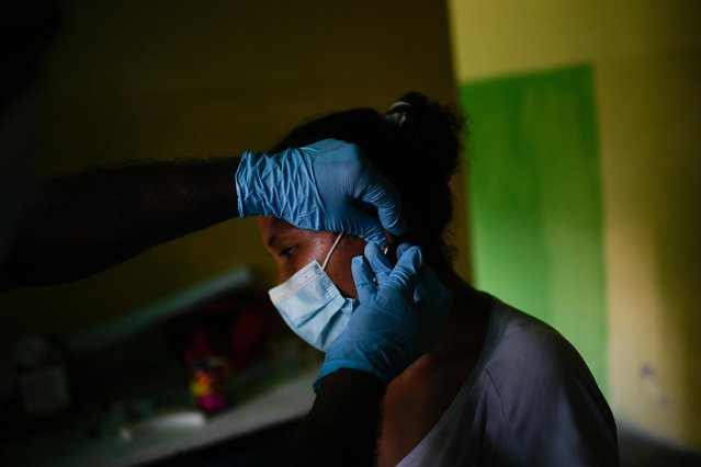 Een hulpverlener in de polikliniek prikt in de oorlel van een patiënt om een bloedmonster af te nemen om te testen op malaria.