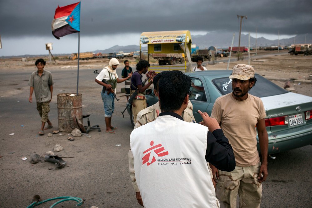 Een medewerker spreekt met gewapende mannen bij een checkpoint in Aden, Jemen, jui 2015. ©Guillaume Binet/MYOP