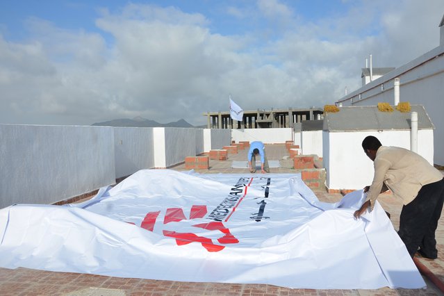 Medewerkers leggen een levensgroot logo op het dak van het ziekenhuis in Taiz, Jemen ter bescherming tegen luchtaanvallen. ©Malak Shaher/MSF