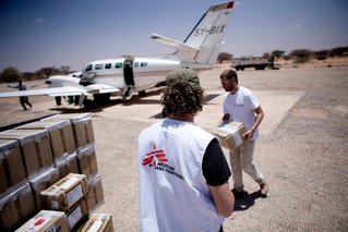 Medewerkers dragen goederen naar het vliegtuig