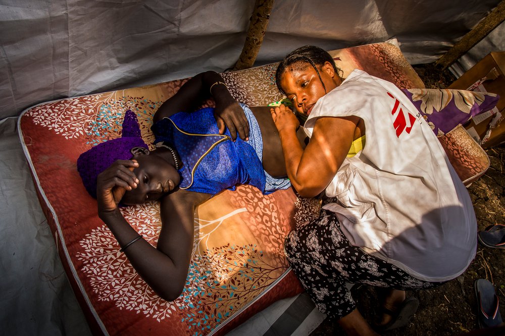 Een hulpverlener van Artsen zonder Grenzen onderzoekt een jonge vrouw in Zuid-Sudan.