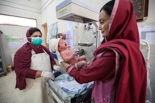 Gezondheidswerker Shabana Shafi houdt liefdevol een pasgeboren baby vast in onze kliniek in Balochistan