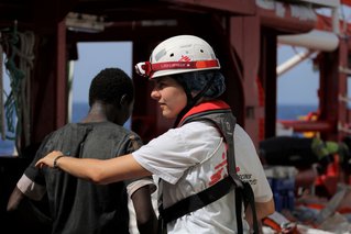 Bemanningslid helpt een jongen aan boord van de Ocean Viking.