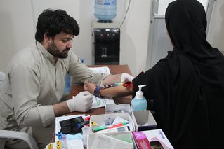 Arts neemt bloed af bij een patiënt in de hepatitis C kliniek in Karachi, India.