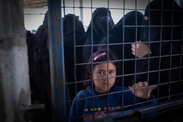 Een jong meisje kijkt door een gesloten hek in het Al-Hol-kamp in het noordoosten van Syrië.