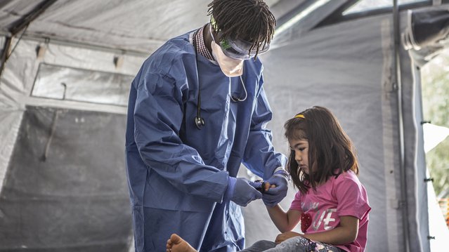 Medewerker Artsen zonder Grenzen werkt in volledig beschermende kleding in het kliniek in kamp Moria, Griekenland