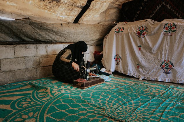 Een gevluchtte Syrische vrouw naait in haar tent in een kamp in Idlib, in Noordwest-Syrië.