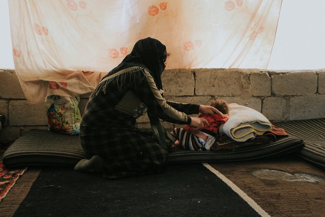 Een gevluchtte vrouw zorgt voor haar dochter in haar tent in een kamp in het Noordwest-Syrië.