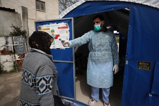 Een arts controleert de temperatuur van een patiënt bij een ziekenhuis in het noorden van Syrië dat door ons ondersteund wordt.