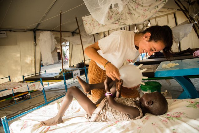 Een verpleegkundige speelt samen met een kind in Zuid-Soedan met een opgeblazen chirurgische handschoen.
