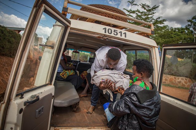 Een medewerker van Artsen zonder Grenzen helpt een dame met een pasgeboren baby uit de ambulance.